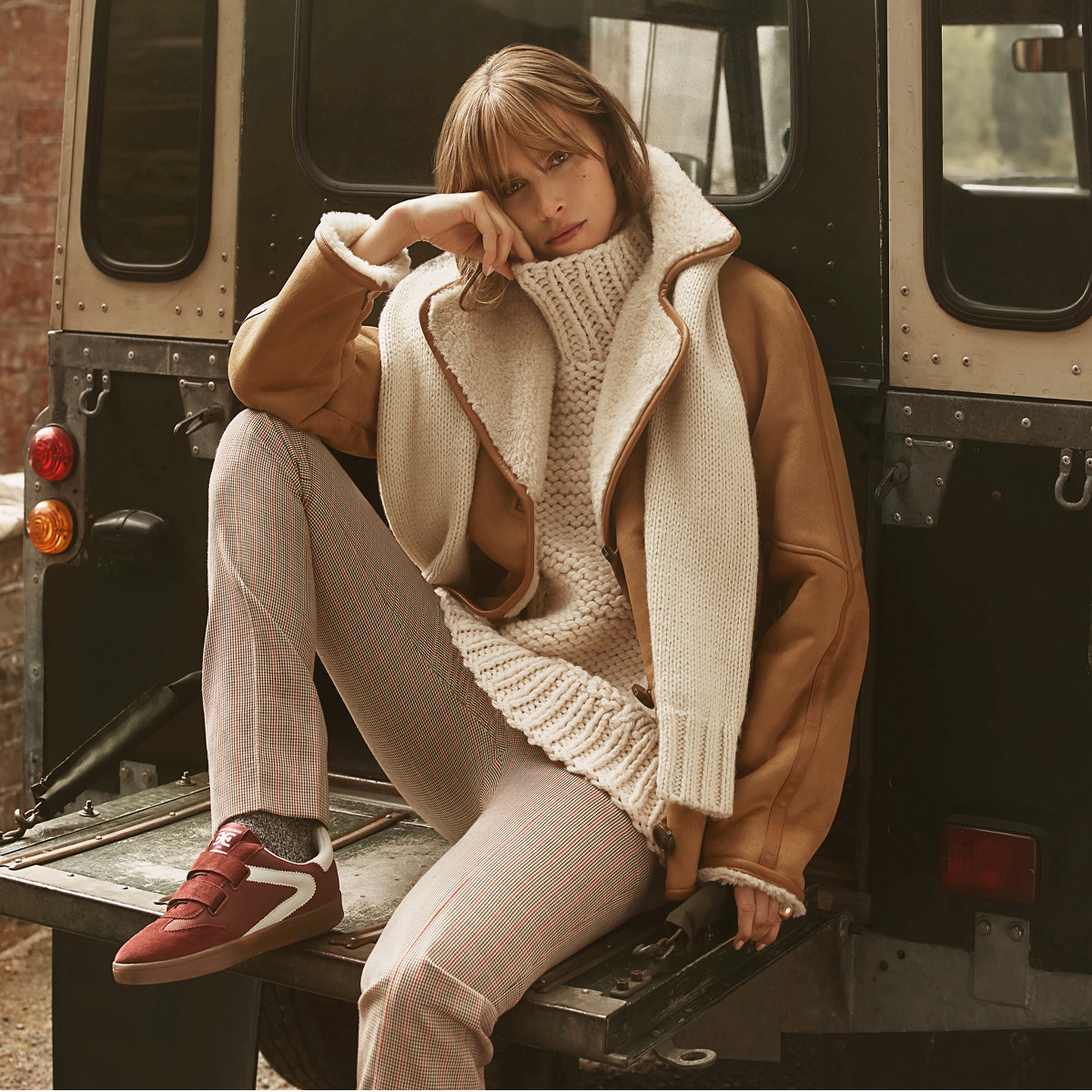 woman dressed in warm clothing, relaxing, wearing the talie velcro sneaker in deep red